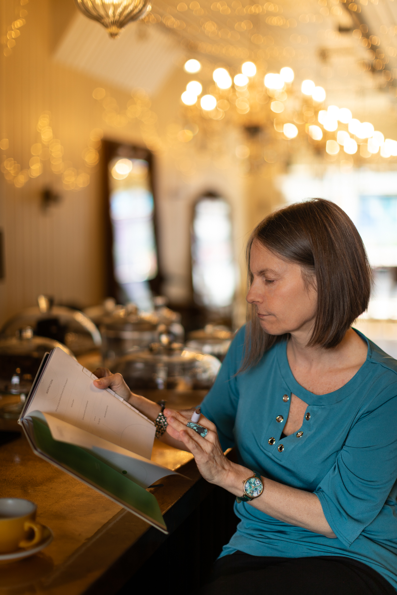Nicky reading through a manuscript in a chandelier-lit tea room