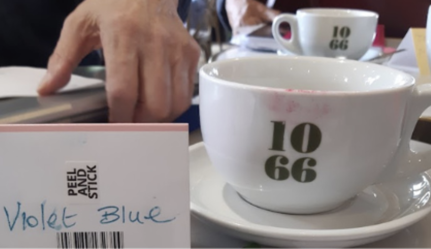 Two 1066 coffee cups on a café table beside a notebook