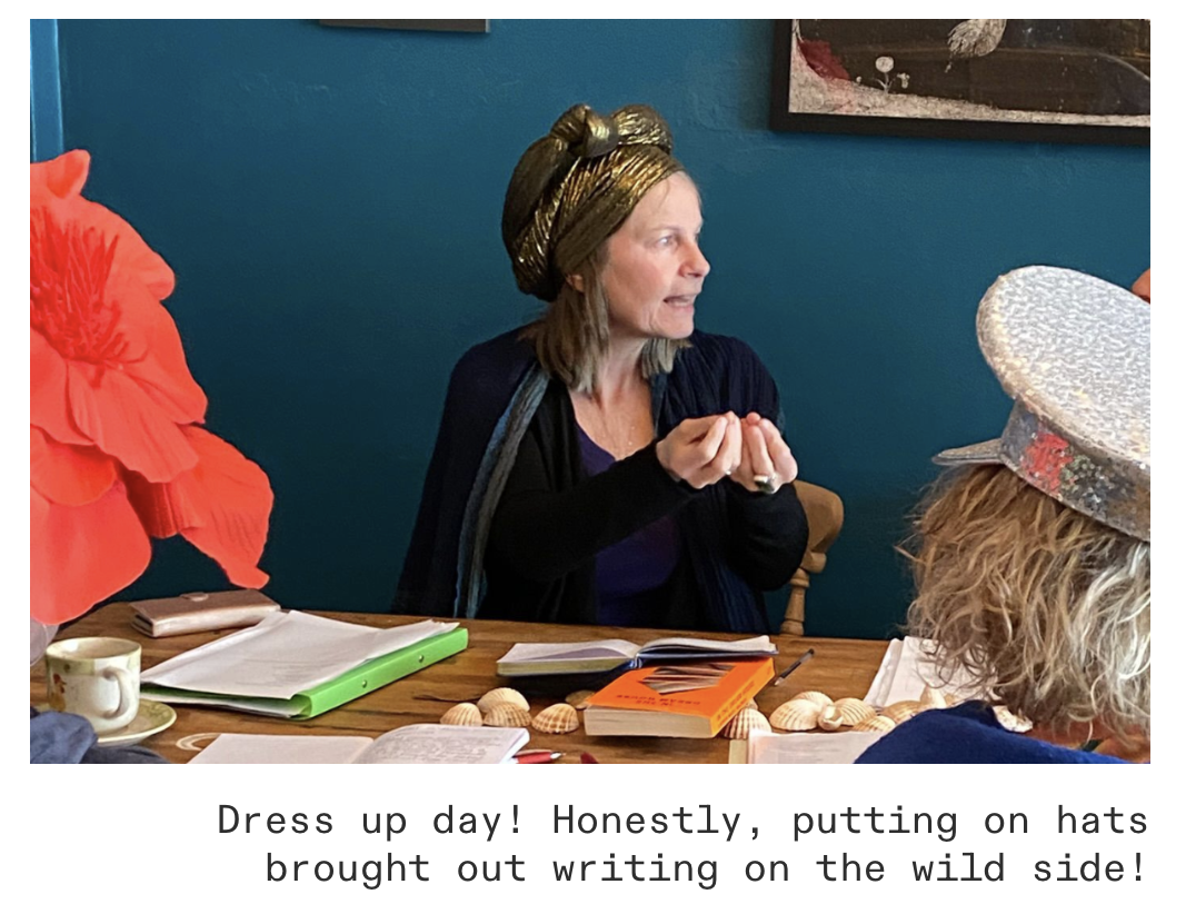 Nicky in a gold headwrap talking animatedly to writers around a table